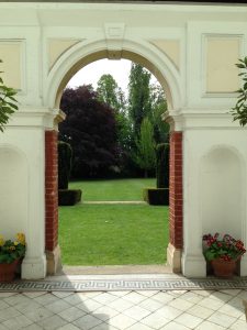 Classical arch through wihch is a view of the lawns.