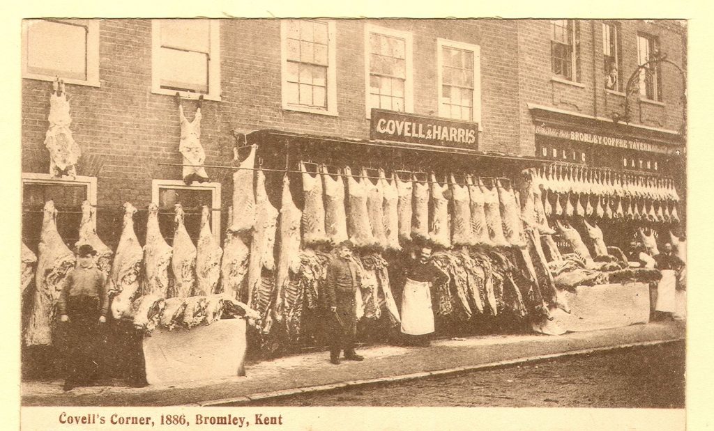 sepia picture of butchers with carcasses hung out for sale