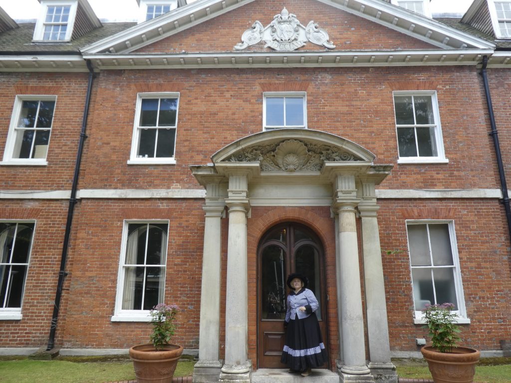 lady in Victoriana dress leaving a columned porch